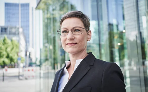 Antje Klötzer-Assion vor der verglasten Fassade eines Bürohochhauses